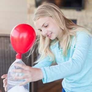 girl doing a science experiment with balloon and bottle