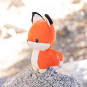 side photo of foxxi plush on a rock