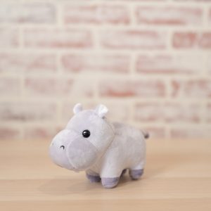 side view of purple hippo plush in front of brick wall