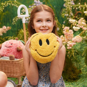 girl holding a yellow smiley face plush